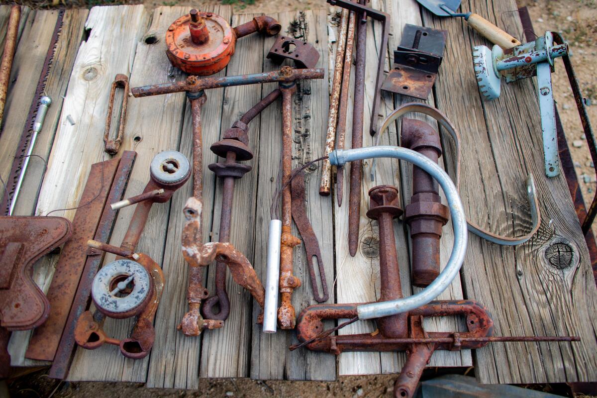 A wooden table full of rusted work tools.