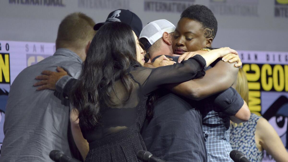 Danai Gurira, right, and from left, Robert Kirkman and Angela Kang, hug Andrew Lincoln at a panel for "The Walking Dead" during Comic-Con International on Friday, July 20, 2018, in San Diego. (Photo by Richard Shotwell/Invision/AP)