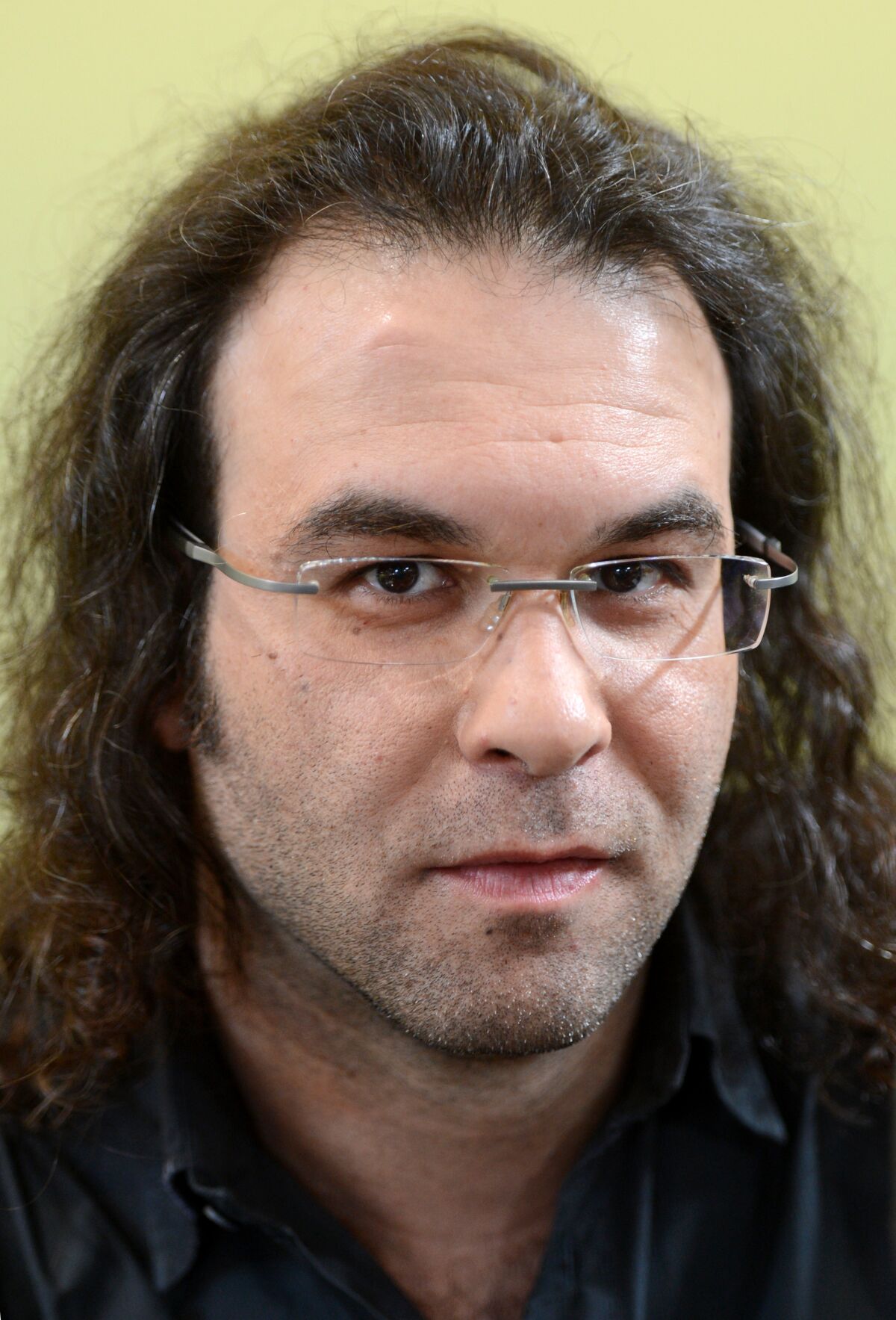 A headshot of a man with glasses and long, wavy hair.