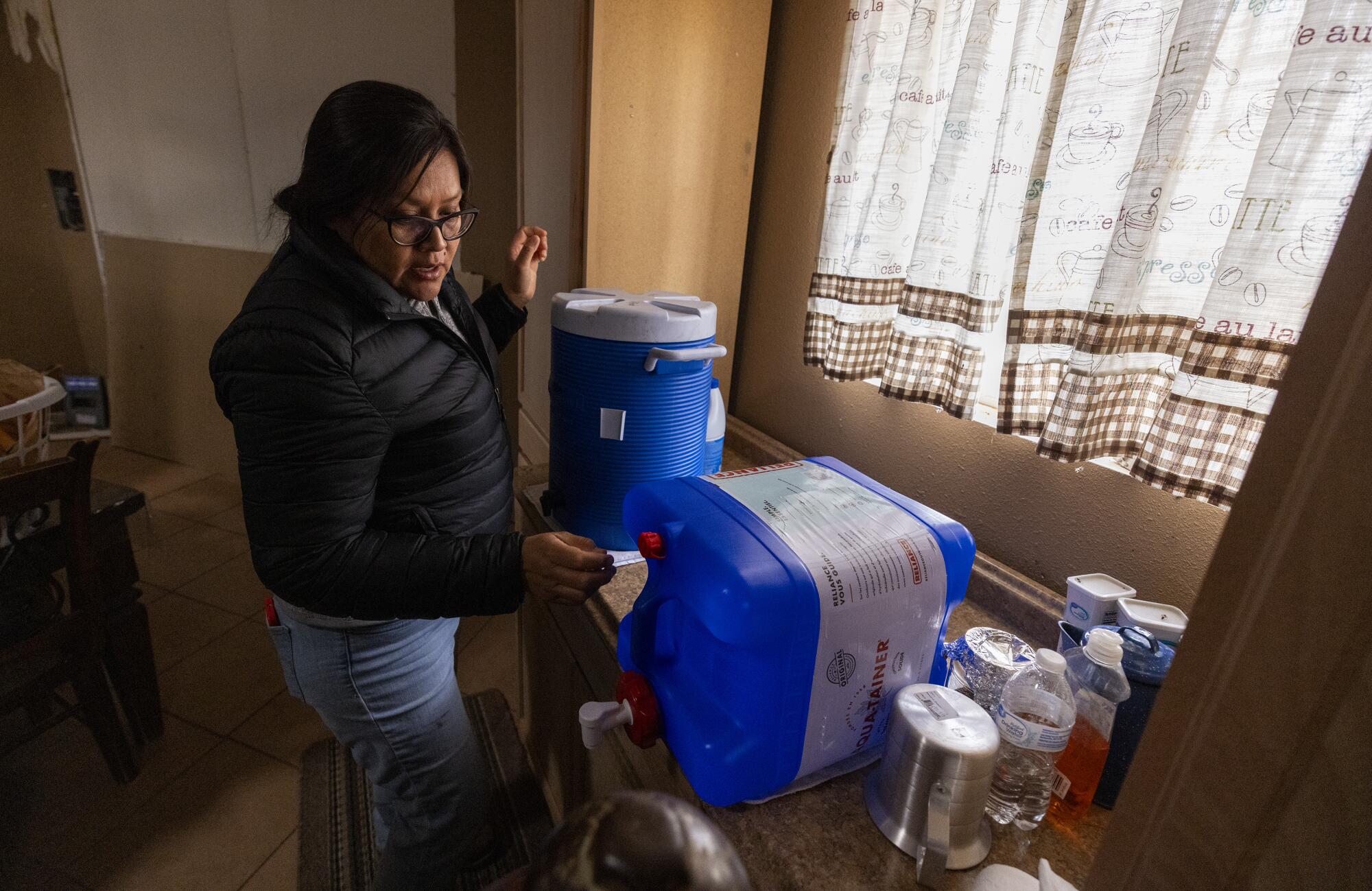 Shanna Yazzie looks over water jugs while completing a survey at the home rural of Alfreda Manheime