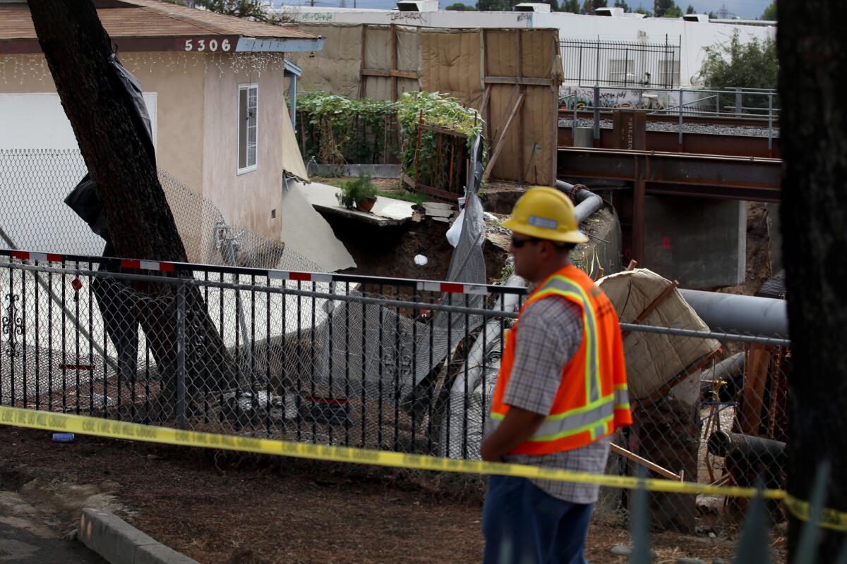 A worker inspects the scene near a red-tagged home after a torrent of water surged through the Rubio Wash and destroyed the back of the home during Tuesday's rainstorm.