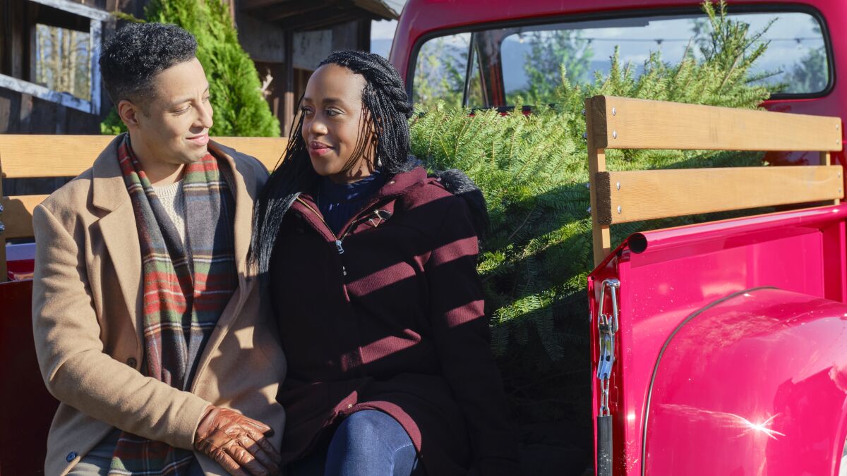 A movie still shows actors in the back of a pickup with a Christmas tree.