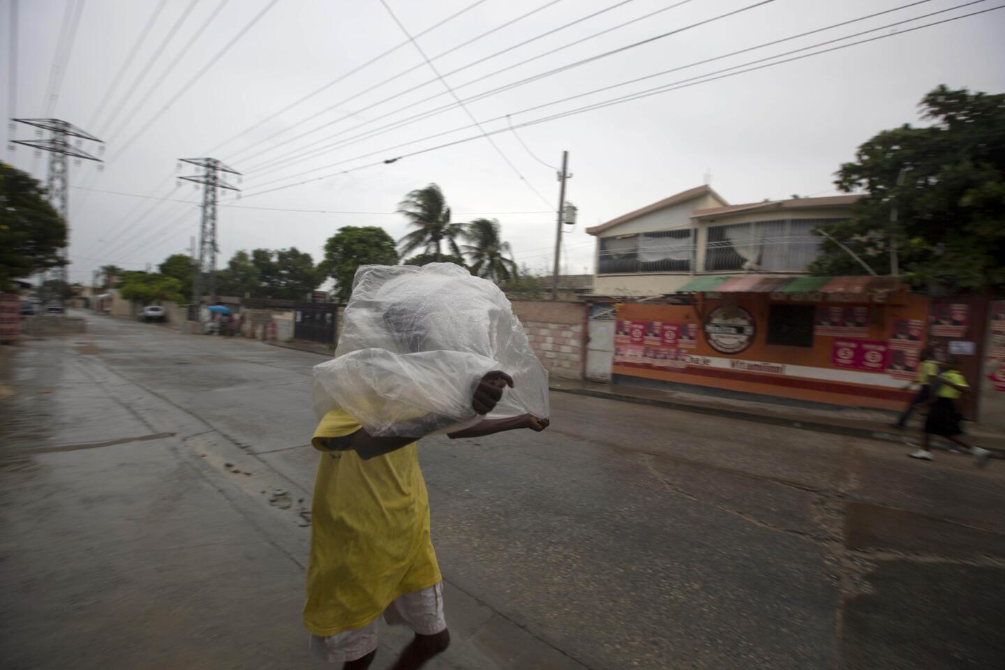 A man crosses a street using a garbage bag as protection from a light rain in Port-au-Prince, Haiti, on Oct. 3, 2016.
