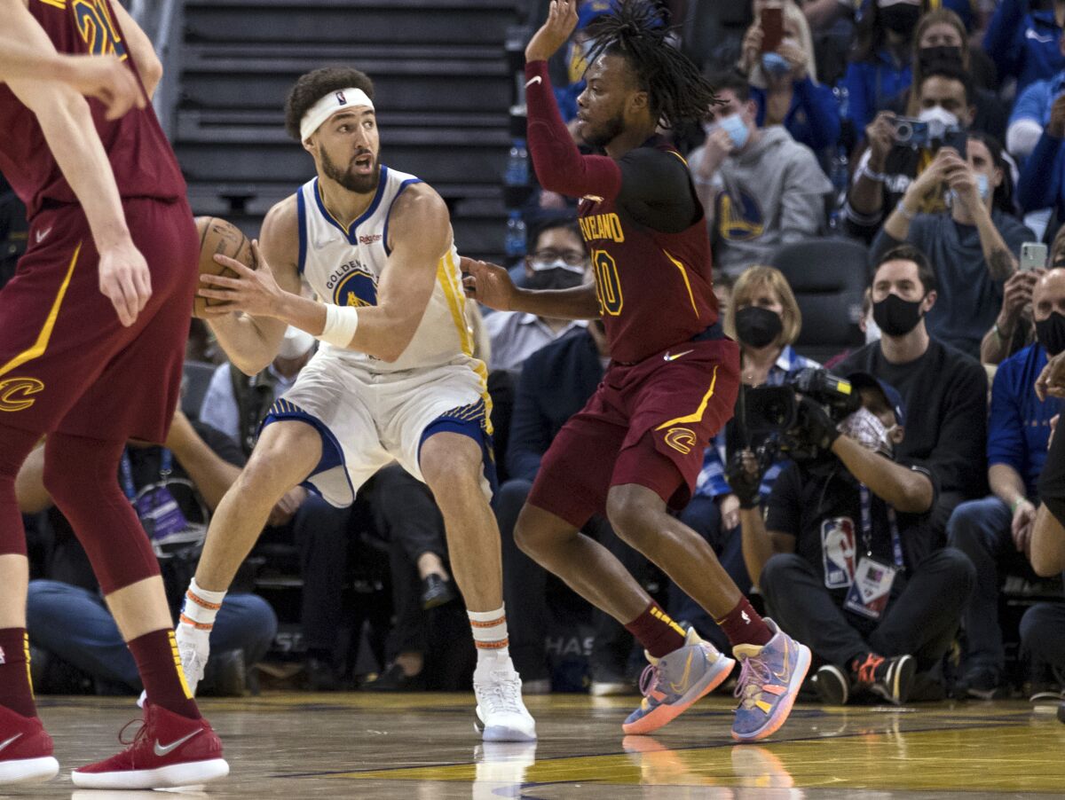 Golden State Warriors guard Klay Thompson, left, looks to pass the ball against Cleveland Cavaliers guard Darius Garland, right, during the first half of an NBA basketball game in San Francisco, Sunday, Jan. 9, 2022. (AP Photo/John Hefti)