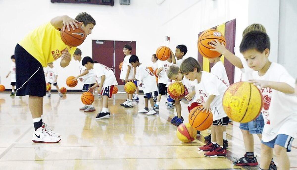 Michael McGlashan, left, leads a dribbling drill at the annual Spartan Basketball Summer Camp.