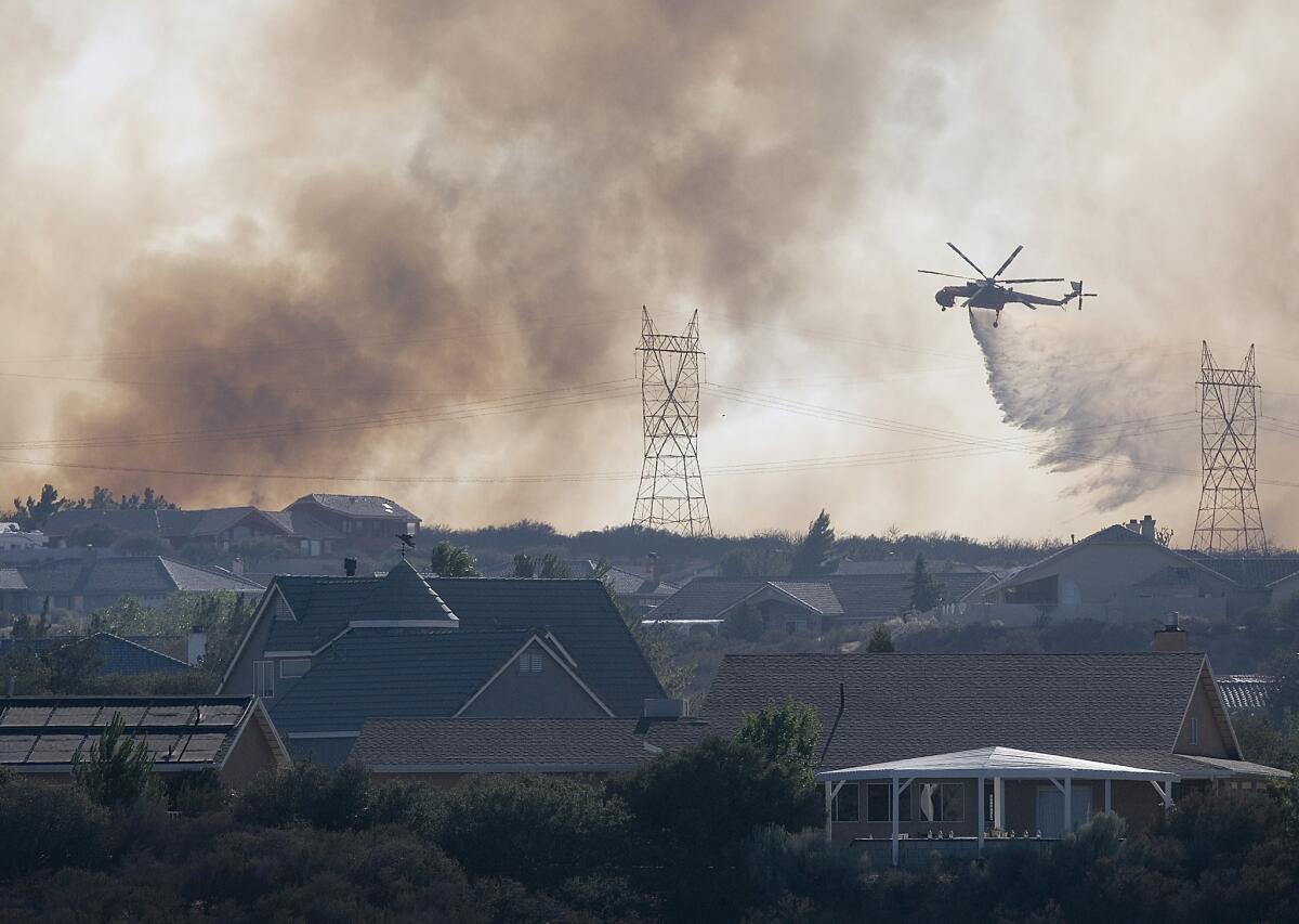 A helicopter works to put out a fire near Oak Hills, Calif., in July.