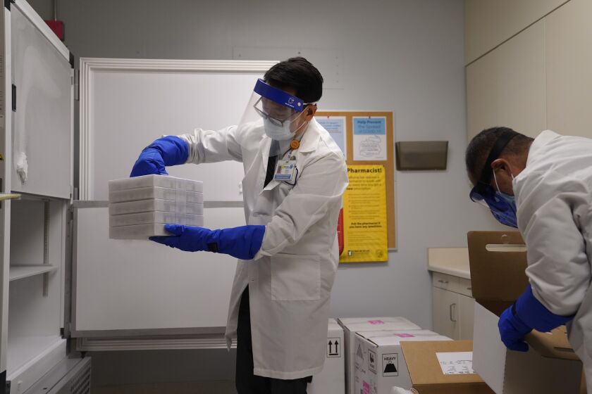Director of inpatient pharmacy David Cheng, center, places trays of the Pfizer-BioNTech COVID-19 vaccine into a freezer at Kaiser Permanente Los Angeles Medical Center in Los Angeles, Monday, Dec. 14, 2020. (AP Photo/Jae C. Hong)