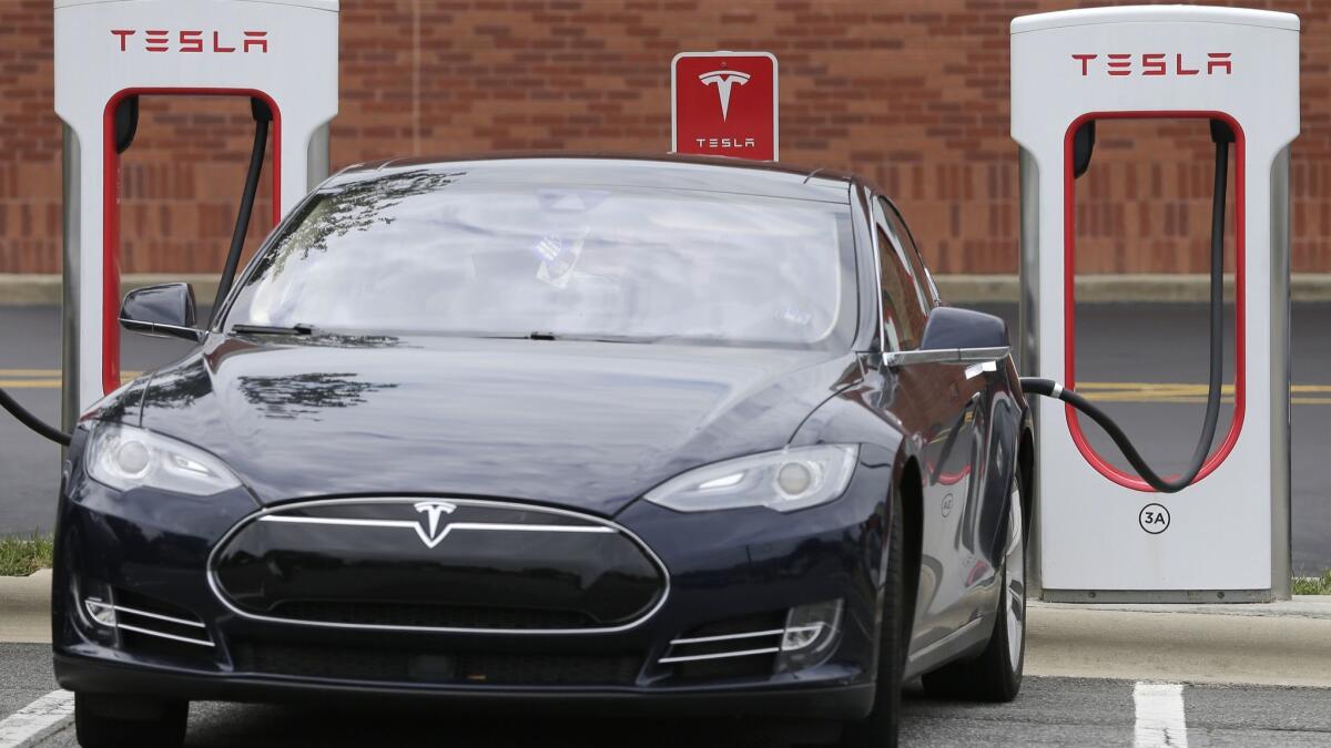 A Telsa Model 3 car plugged in at a Tesla charging station in 2017.