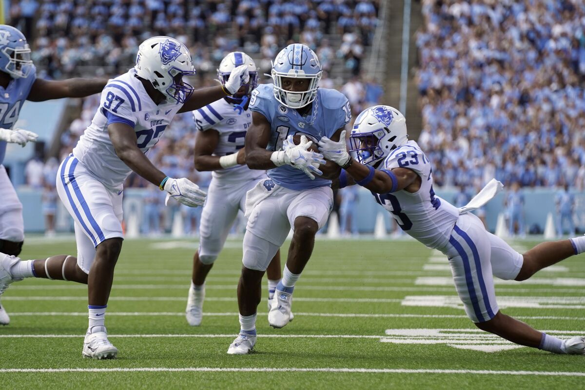 North Carolina running back Ty Chandler (19) runs while Duke defensive end Caleb Oppan (97) and Duke safety Lummie Young IV (23) reach to tackle during the second half of an NCAA college football game in Chapel Hill, N.C., Saturday, Oct. 2, 2021. (AP Photo/Gerry Broome)