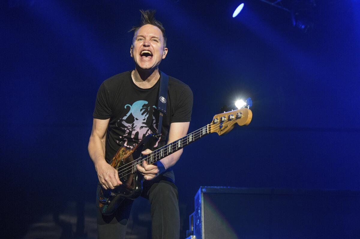 A man wearing a short-sleeved T-shirt plays guitar onstage.