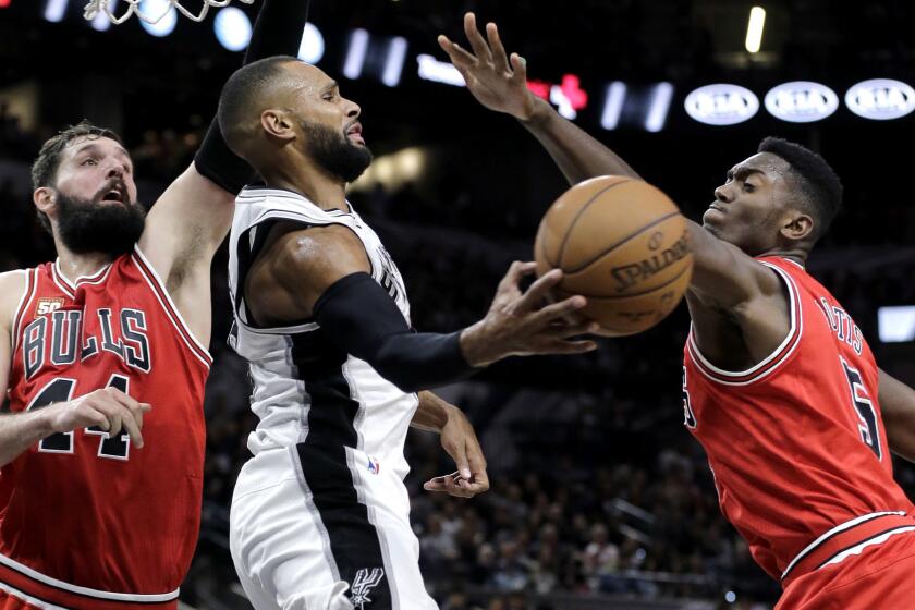 FILE - In this March 10, 2016, file photo, San Antonio Spurs guard Patty Mills, center, passes the ball as he is pressured by Chicago Bulls forward Nikola Mirotic (44) and forward Bobby Portis (5) during the second half of an NBA basketball game, in San Antonio. The Bulls have suspended forward Bobby Portis for the first eight games for injuring teammate Nikola Mirotic during a fight at practice. Mirotic suffered multiple broken bones in his face as well as a concussion on Tuesday. He will likely need surgery and is out indefinitely. The team announced the suspension on Wednesday, Oct. 18, 2017. (AP Photo/Eric Gay, File)