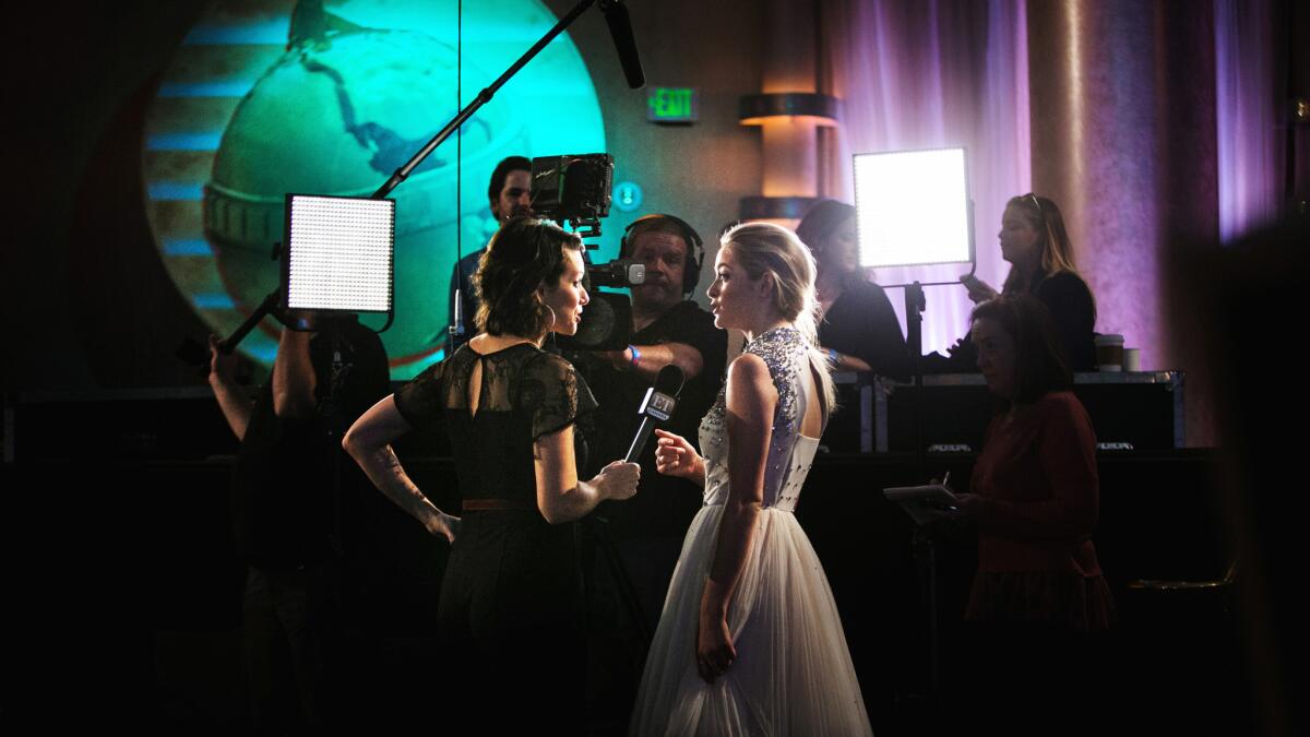 Greer Grammer, Miss Golden Globe 2015, right, is interviewed by a television reporter during the Golden Globes preview day at the Beverly Hilton.