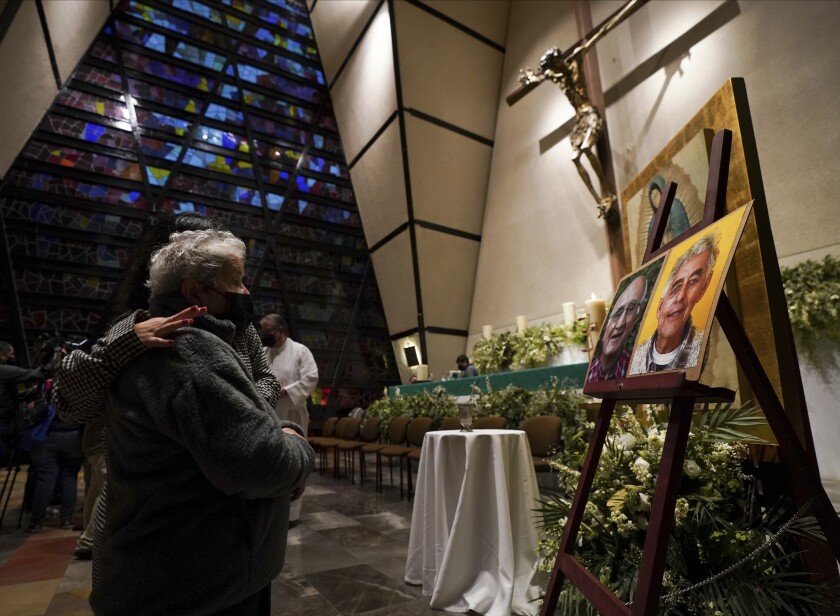 Faithful mourn in front of the photos of Jesuit priests Javier Campos Morales and Joaquin Cesar Mora Salazar during a Mass at a church in Mexico City, Tuesday, June 21, 2022. The two elderly priests were killed inside a church where a man pursued by gunmen apparently sought refuge in a remote mountainous area of northern Mexico, the religious order's Mexican branch announced Tuesday. (AP Photo/Fernando Llano)