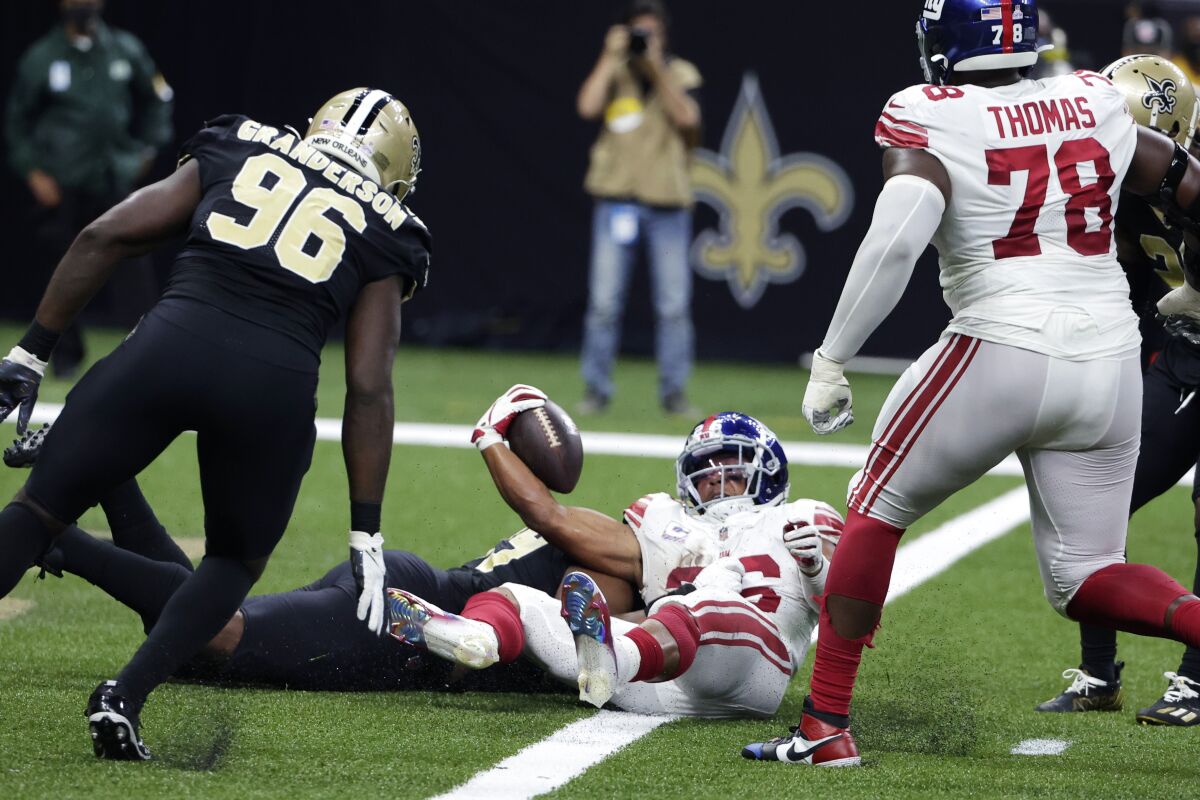 New York Giants running back Saquon Barkley (26) scores a touchdown against New Orleans Saints defensive end Carl Granderson (96) and defensive tackle Shy Tuttle to win in overtime during an NFL football game in New Orleans, Sunday, Oct. 3, 2021. The Giants won 27-21. (AP Photo/Derick Hingle)