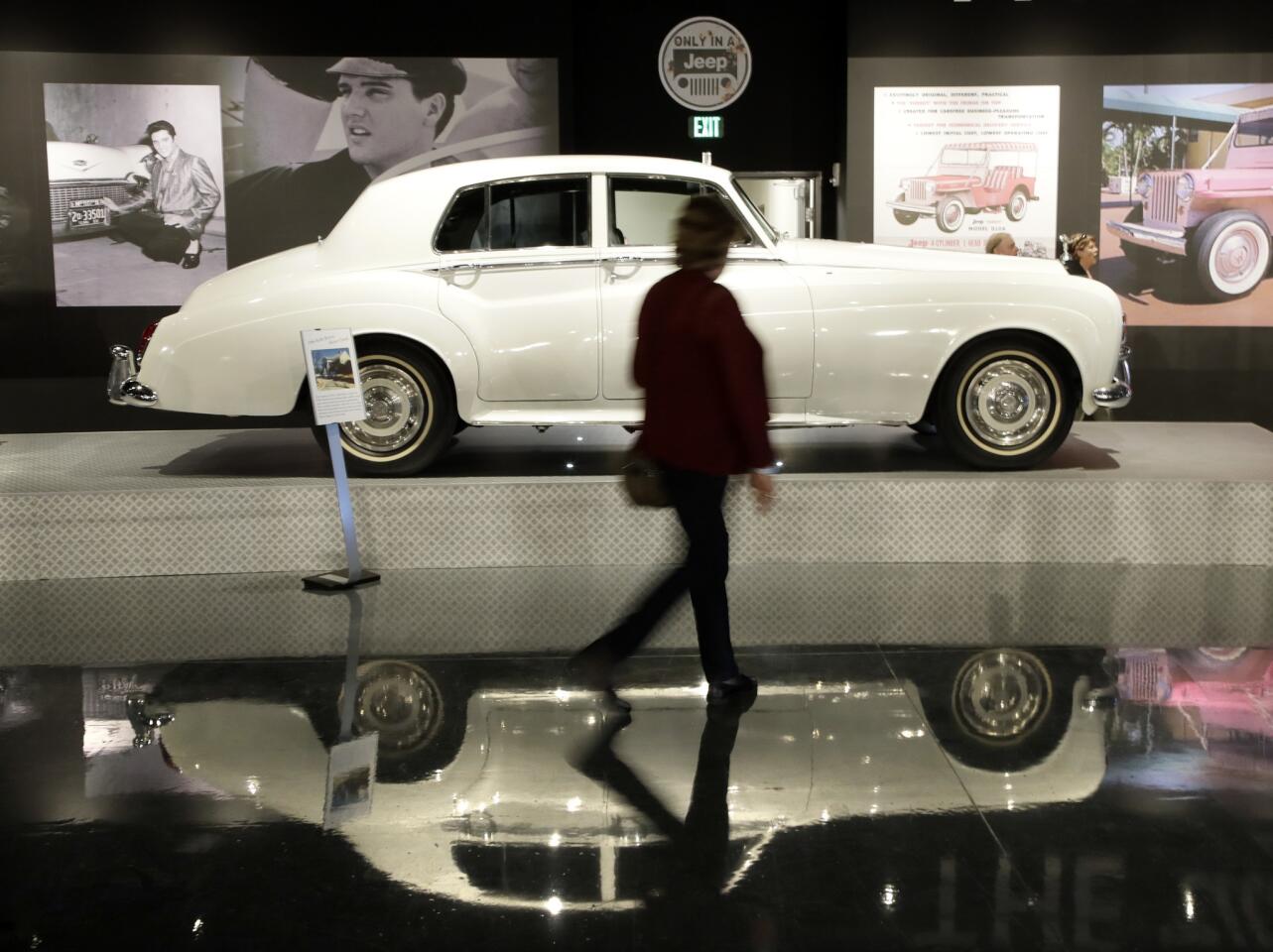 A woman walks past one of Elvis Presley's cars displayed at the "Elvis Presley's Memphis" complex
