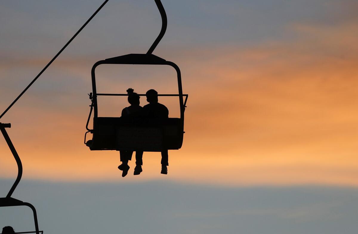 A couple take in the sunset as they ride along on the Sky Ride from one side of the fair to other at the OC Fair.