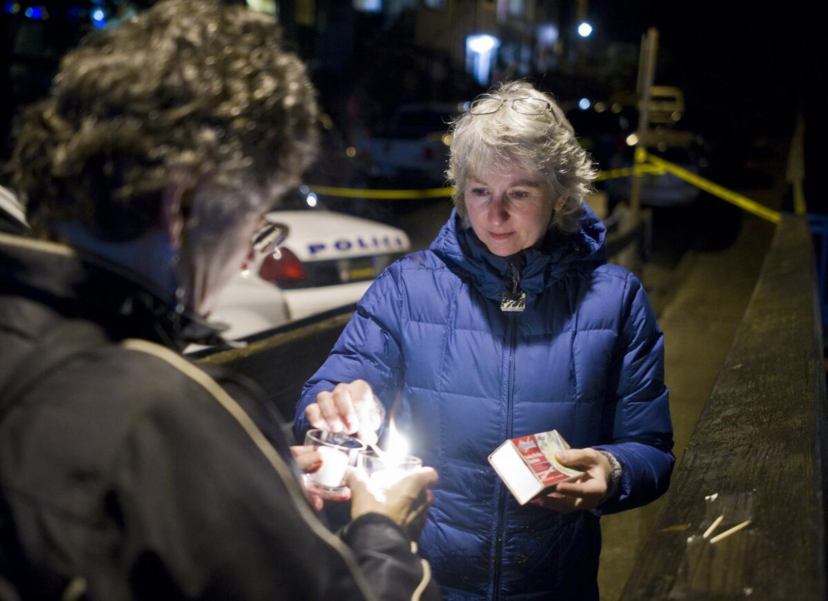 D.J. Thomson, right, and Joyce Levine light candles on Kennedy Street in downtown Juneau for Mayor Greg Fisk, who was found dead in his home this week.