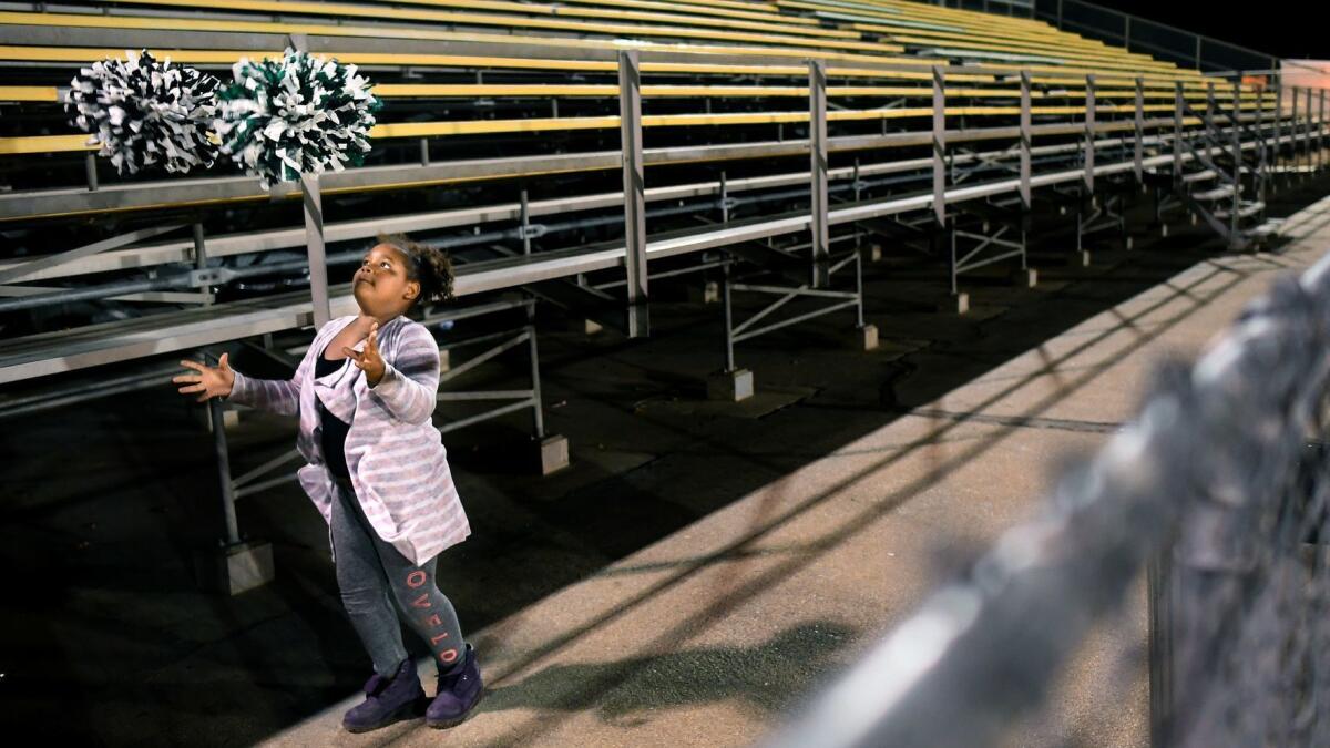 Sanai Mayfield plays with pom-poms on the Hawkins High side of the bleachers during a football playoff game at San Fernando in 2017.