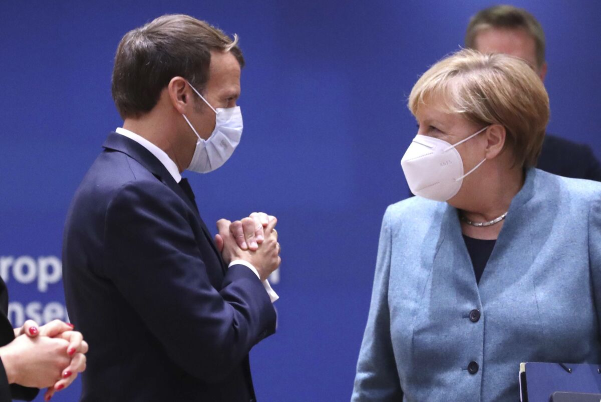 German Chancellor Angela Merkel, right, speaks with French President Emmanuel Macron arrives for a round table meeting at an EU summit at the European Council building in Brussels, Thursday, Oct. 15, 2020. European Union leaders are meeting in person for a two-day summit amid the worsening coronavirus pandemic to discuss topics ranging from Brexit to climate and relations with Africa. (Yves Herman, Pool via AP)