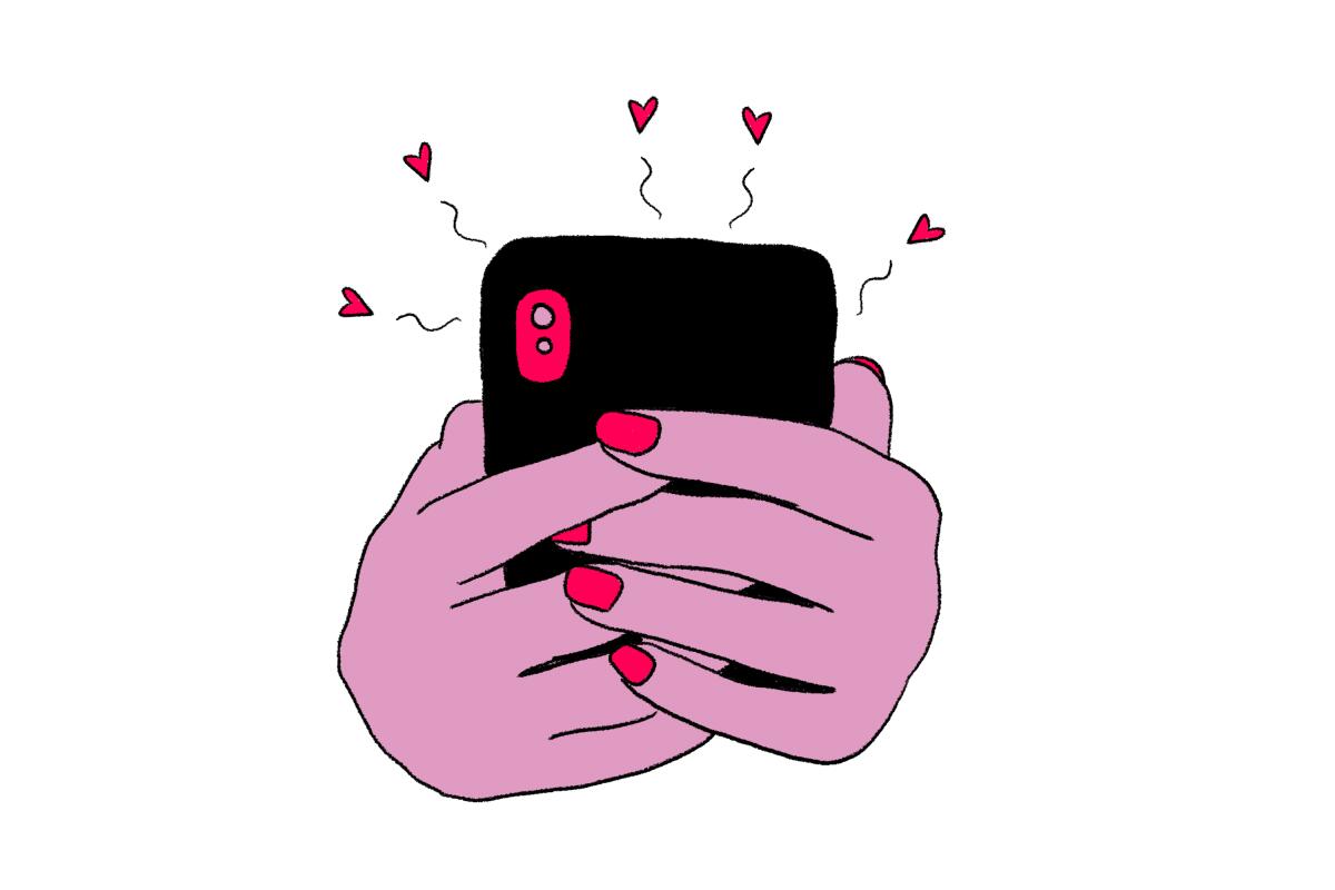 Manicured hands holding a smartphone that's emitting hearts.