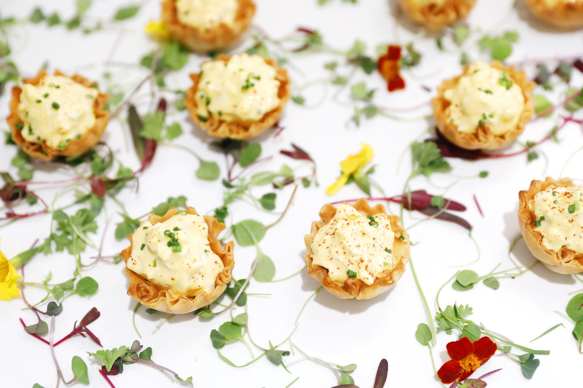 Deviled egg salad in phyllo cups on a floral tablecloth