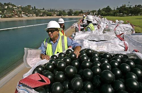 DWP worker Manuel Martinez waits for the signal to empty out bales of black balls into the Ivanhoe Reservoir in Los Angeles. The Department of Water and Power released about 400,000 4-inch black plastic balls as the first installment of approximately 3 million balls that will form a floating cover over the reservoir.