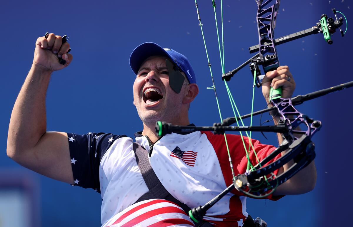 Jason Tabansky raises a clenched fist while holding his bow in his other hand.