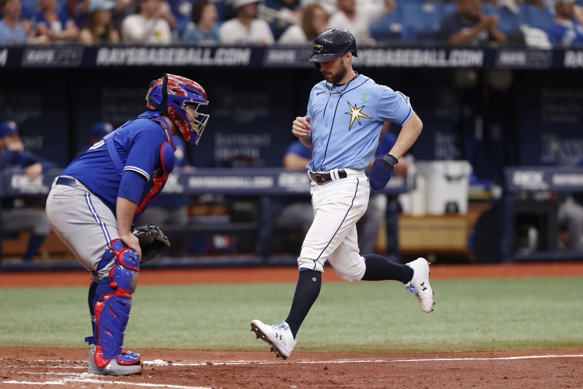 Tampa Bay Rays' Brandon Lowe, right, scores past Toronto Blue Jays catcher Alejandro Kirk during the sixth inning of a baseball game Sunday, May 15, 2022, in St. Petersburg, Fla. (AP Photo/Scott Audette)
