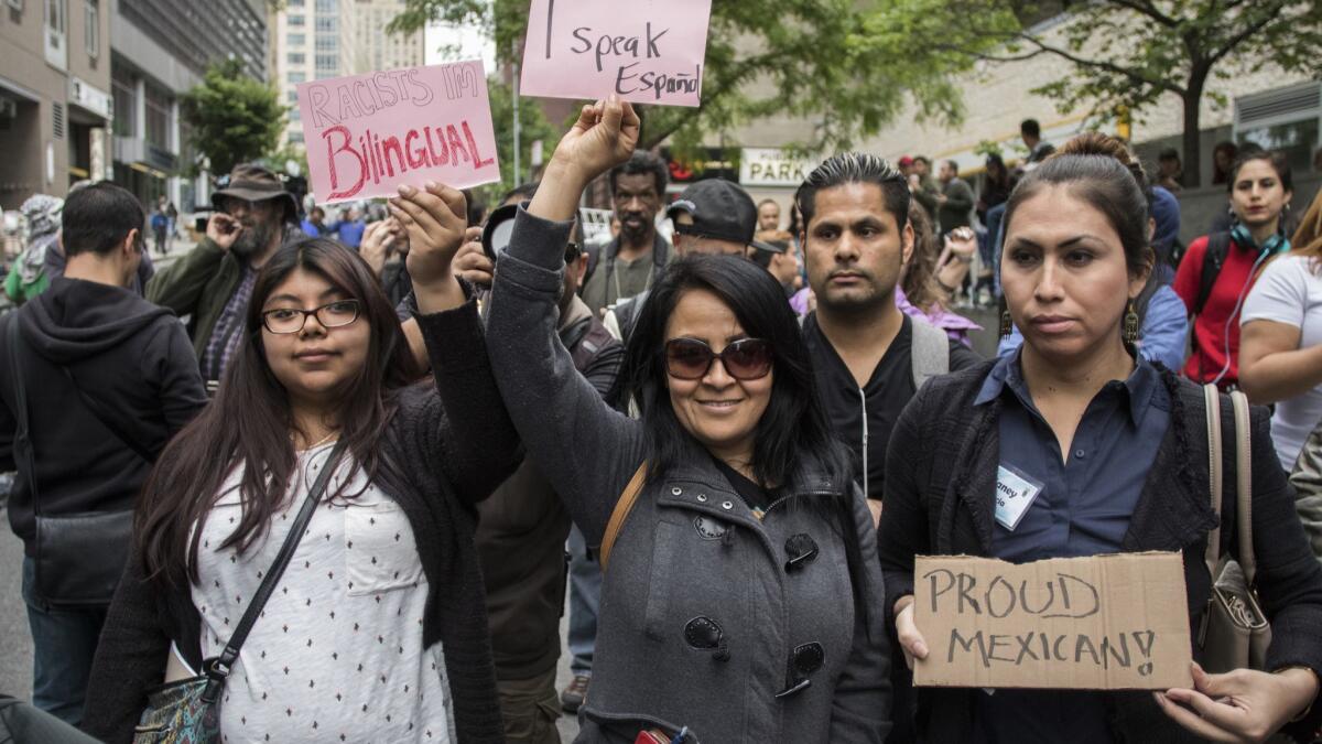 Participants at a rally organized by New York's immigrant and Latino communities hold up signs protesting lawyer Aaron Schlossberg's racist comments.