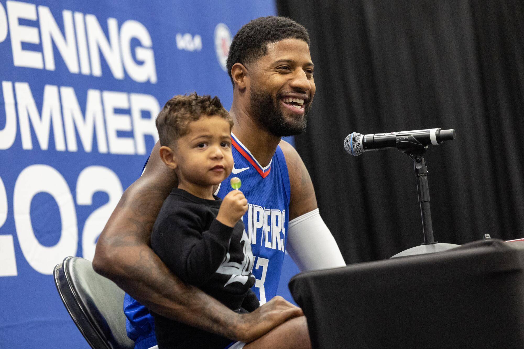 Paul George addresses reporters during media day with his son, Paul Vuk, sitting in his lap.
