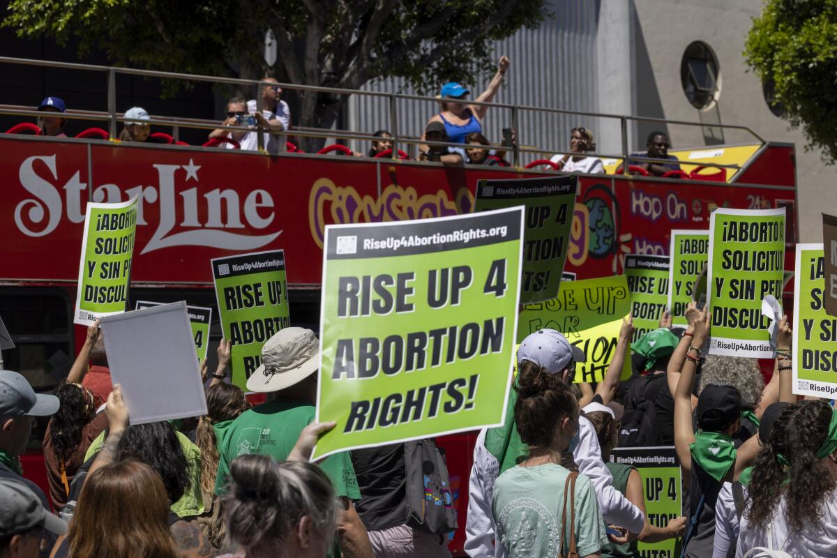 A sightseeing bus passes protesters marching on Hollywood Boulevard to support abortion rights.