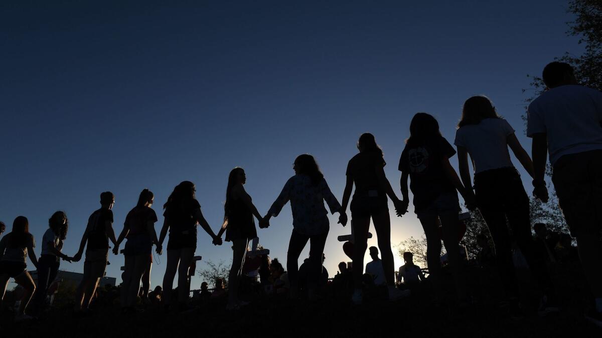 Students and their family members join hands outside Marjory Stoneman Douglas High School n Parkland, Fla.