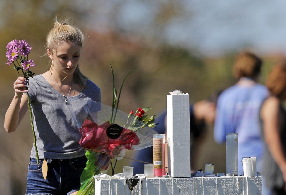A woman places flowers at one of 17 crosses placed for the victims of the shooting at Marjory Stoneman Douglas High School in South Florida on Feb. 14.
