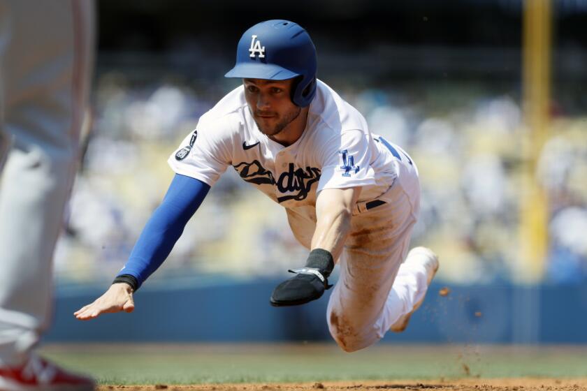 Los Angeles Dodgers' Trea Turner dives back to first base to tag up on a fly ball hit by Max Muncy during the second inning of a baseball game against the Los Angeles Angels in Los Angeles, Sunday, Aug. 8, 2021. (AP Photo/Alex Gallardo)