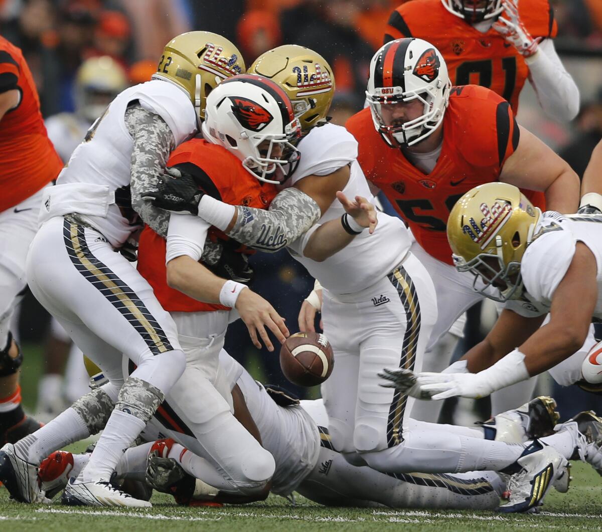 Oregon State quarterback Nick Mitchell fumbles the ball while being tackled by a pair of UCLA defenders during the first half of a game on Nov. 7.