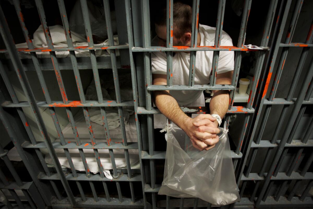 An inmate leans out the bars of his cell.