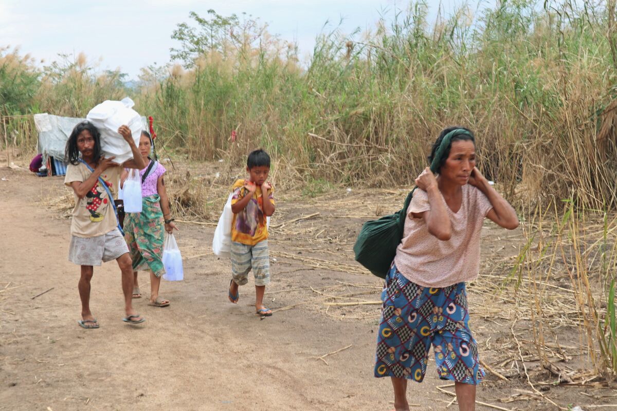 Displaced people from Myanmar walking on a dirt path