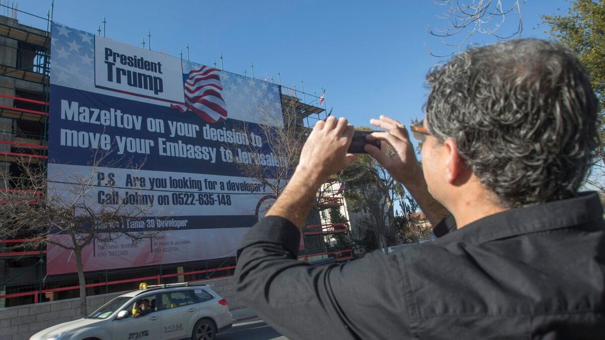 An Israeli man in Jerusalem on Friday photographs a banner congratulating President Donald Trump on his pledge to move the U.S. embassy in Israel from Tel Aviv to Jerusalem.