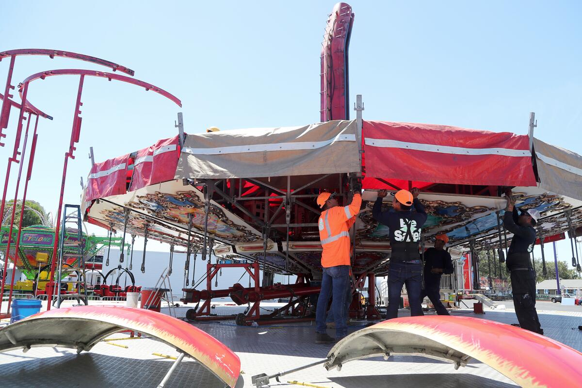 A crew sets up a carousel ride Friday in advance of the July 15 start of the annual Orange County Fair in Costa Mesa. 