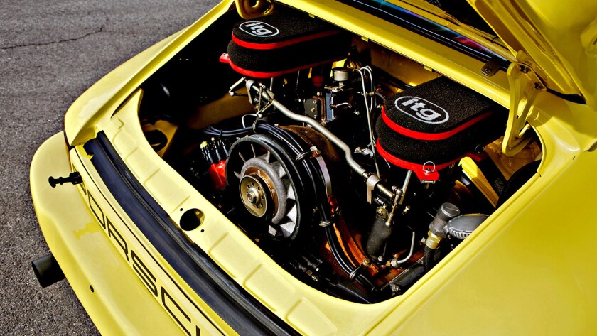 The rear lid on a yellow 1974 Porsche 911 Carrera 3.0 IROC RSR is open to reveal the engine inside