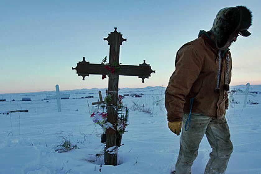 PAYING RESPECTS: Thomas Cheemuk visits the grave of his brother John, who killed himself in 1999, in a cemetery overlooking the Alaska village of St. Michael in February.