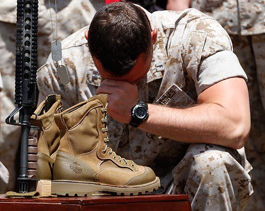 A Marine pauses in front of an inverted rifle display at Camp Pendleton, where dog tags and empty boots on a wooden box symbolize the death of a fallen comrade. A memorial service Friday honored 25 troops from the 3rd Battalion, 5th Regiment, who were killed and more than 200 who were wounded during a seven-month campaign to drive the Taliban from the Sangin district of Afghanistan's Helmand province. See full story