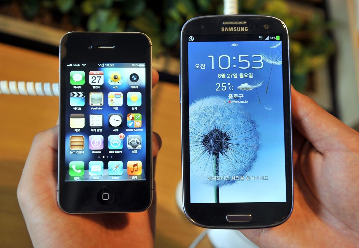 An employee shows an Apple iPhone 4s, left, and a Samsung's Galaxy S3 at a store in Seoul in 2012.