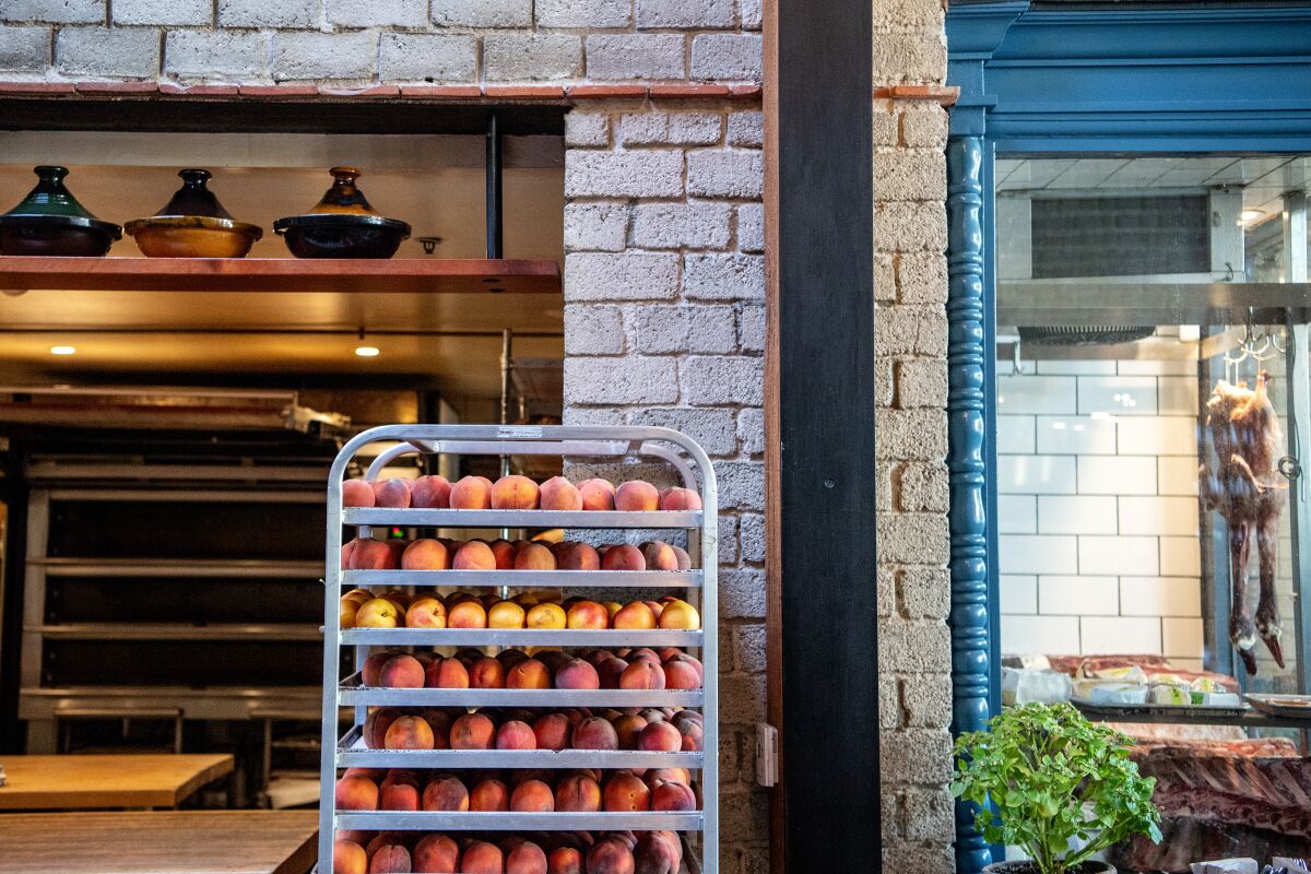 Stone fruits ripening on a tiered metal rack at République