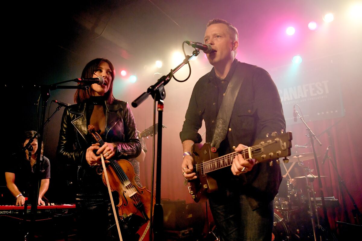 Amanda Shires and Jason Isbell sing and play musical instruments onstage.