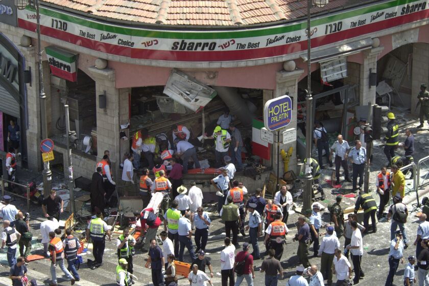 EDS NOTE: GRAPHIC CONTENT - FILE - Police and medics surround the scene of a bomb explosion in a restaurant downtown Jerusalem, Aug. 9, 2001. An Israeli hospital says a woman critically wounded in a 2001 suicide bombing at a Jerusalem restaurant has died. Her death marked the sixteenth fatality from that attack. (AP Photo/Peter Dejong, File)