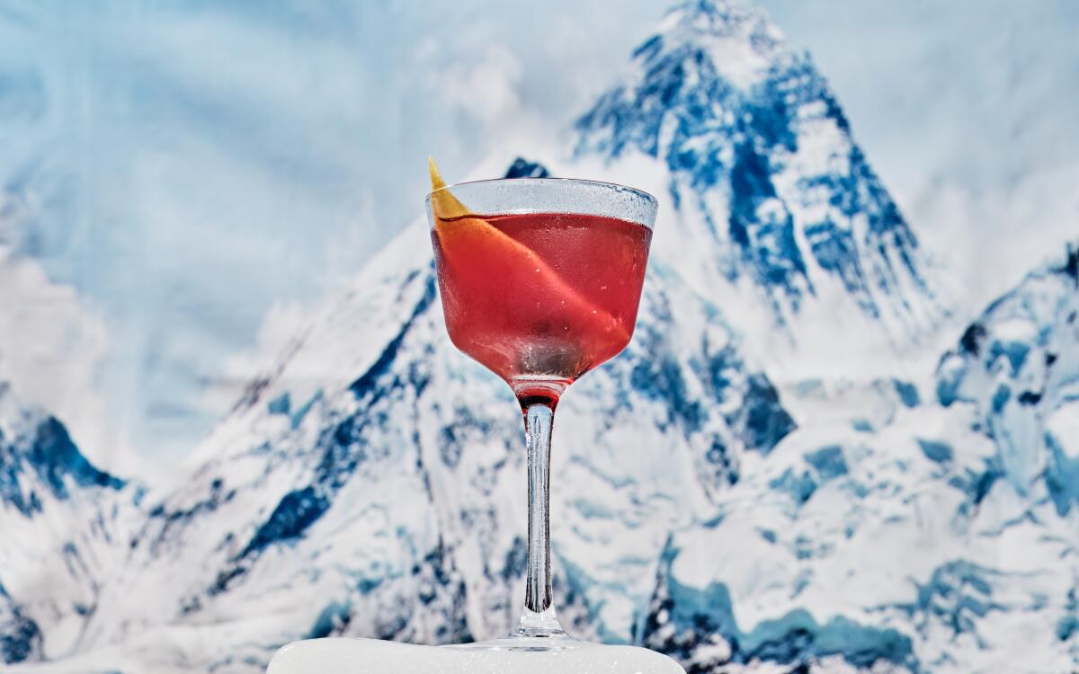 A drink in a stemmed glass with a snow-covered mountain in the background
