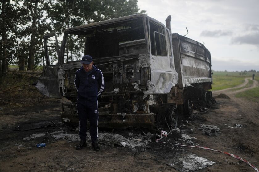 Vadym Schvydchenko stands next to his truck recentely damaged by a mine on a dirt track near Makariv, on the outskirts of Kyiv, Ukraine, Tuesday, June 14, 2022. The detonation of the 7.5-kilogram (16-pound) explosive charge blew Vadym Schvydchenko and his daughter's toy clean out of the cabin. The truck — and his livelihood — went up in flames. (AP Photo/Natacha Pisarenko)