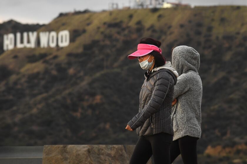 LOS ANGELES, CALIFORNIA MARCH 23, 2020-Hikers wearing masks because of the coronavirus walk past the Hollywood sign in Griffith Park Monday. (Wally Skalij/Los Angeles Times)