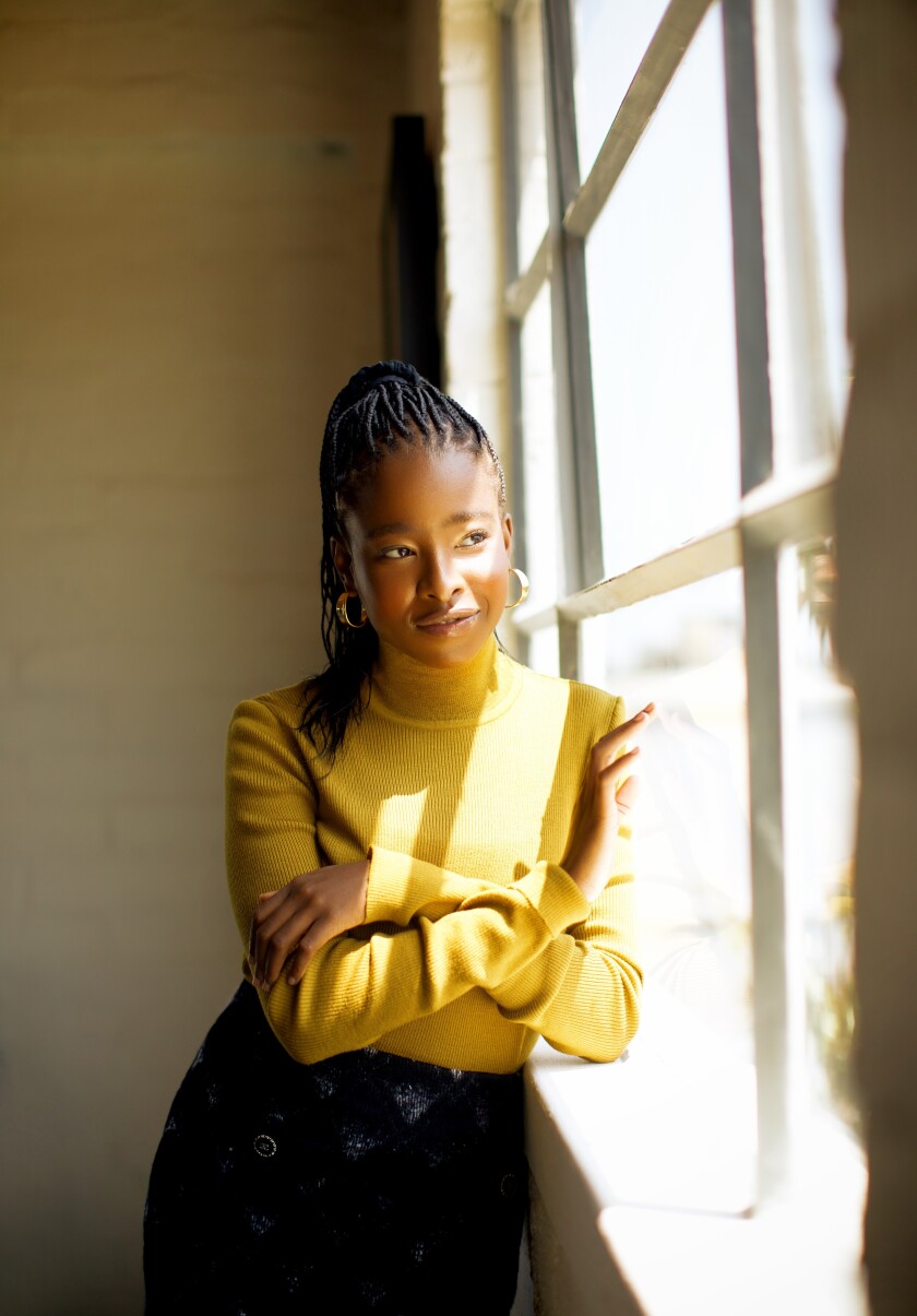 Los Angeles poet Amanda Gorman leans against a window, looking out.